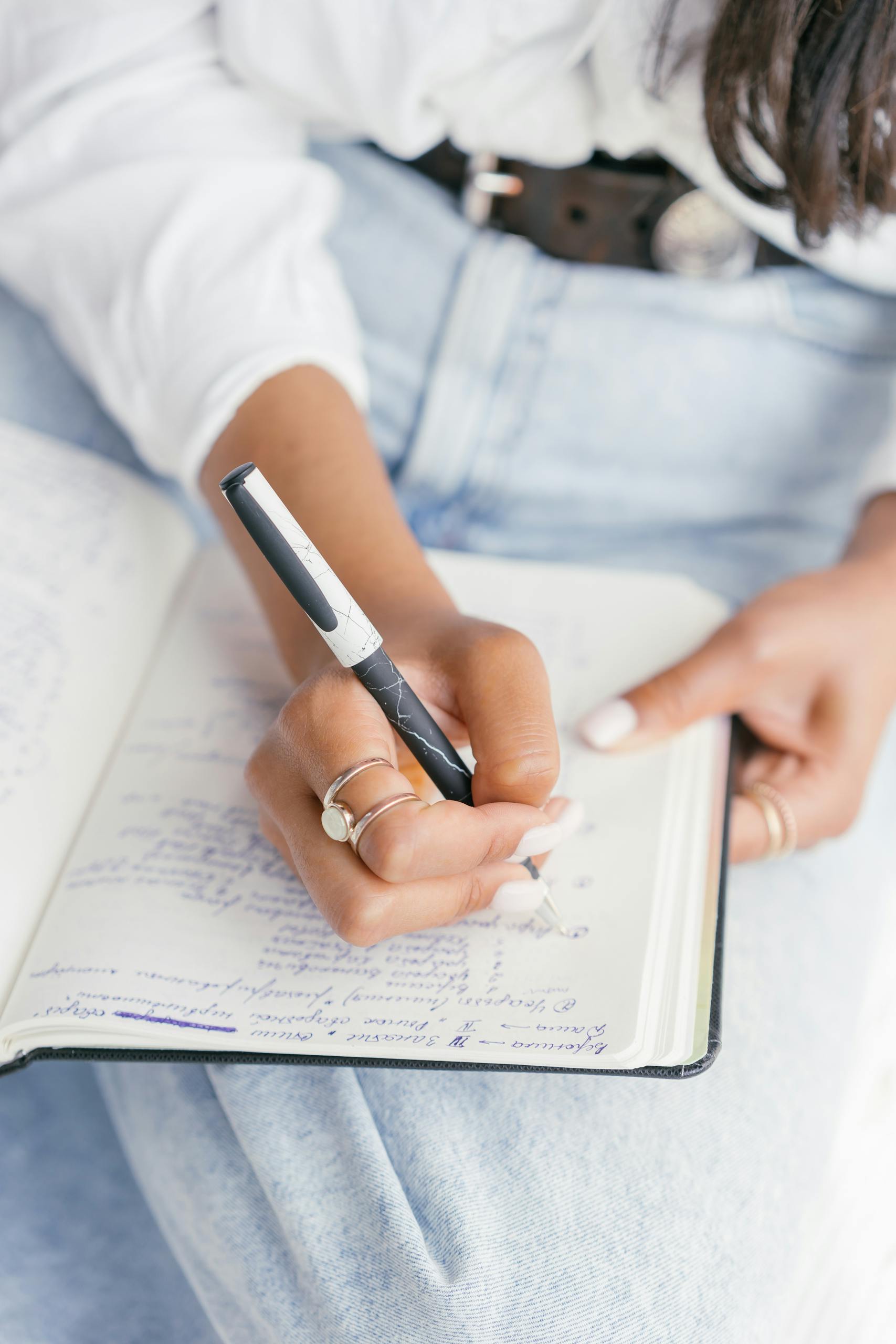 Woman writing in a notebook, emphasizing focus and creativity in an educational setting.